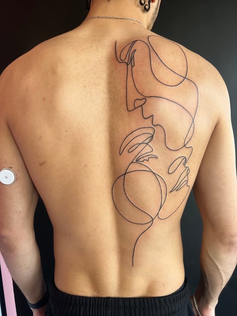 Back view of shirtless person displaying a continuous line art tattoo design running vertically down the spine