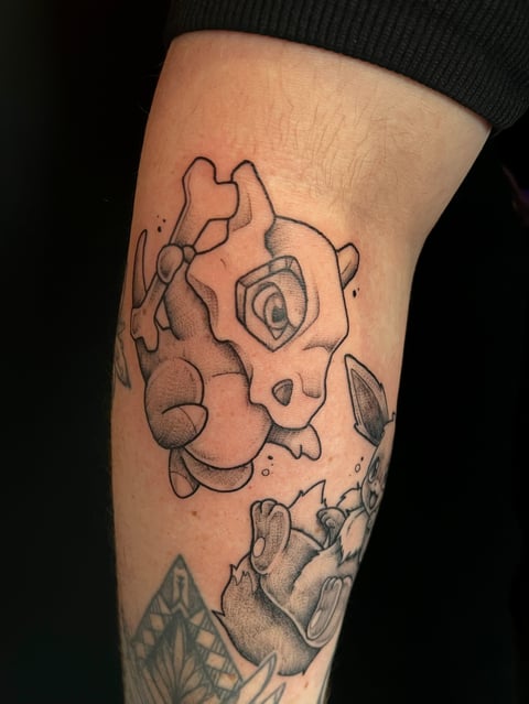 Black and gray sketch-style tattoo of an abstract creature with multiple eyes and organic shapes on a persons leg