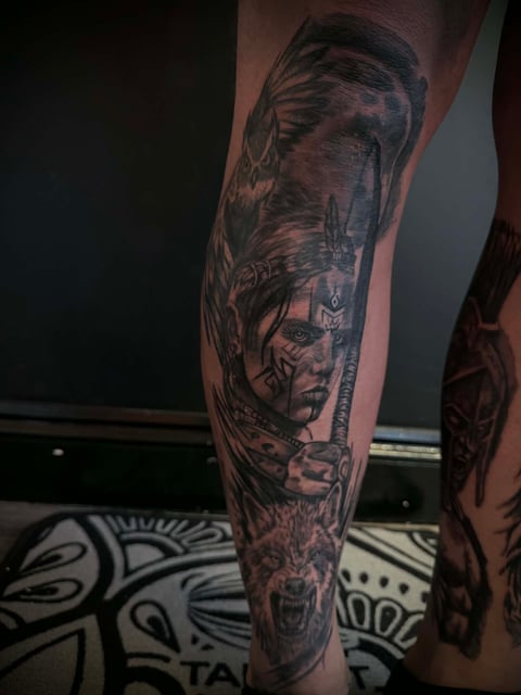Full leg sleeve tattoo featuring portrait and nature imagery in black ink on human leg