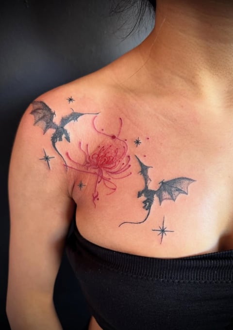 Person's shoulder tattoo featuring a red flower surrounded by black flying bats and small stars